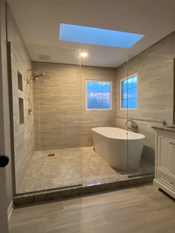 This may contain: a bath room with a tub a sink and a window on the side of it