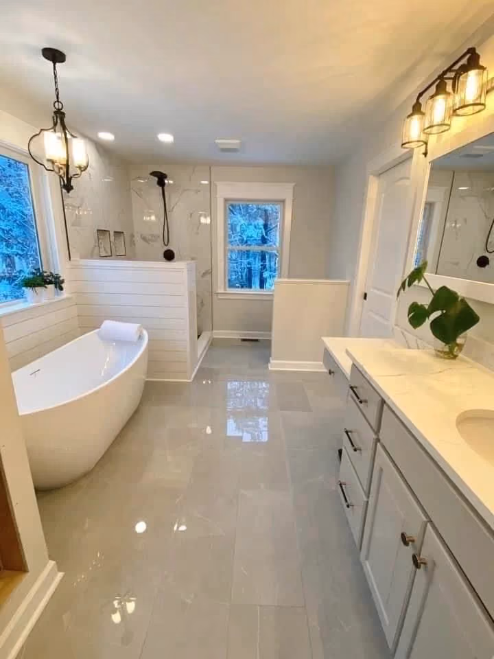 This may contain: a large white bathroom with an oval tub and double sinks