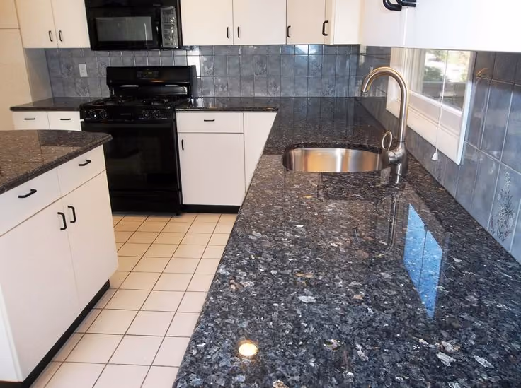 This may contain: an empty kitchen with granite counter tops and white cupboards, black appliances and stainless steel sink