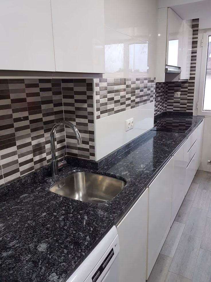 This may contain: a kitchen with black granite counter tops and white cabinets, along with a stainless steel sink