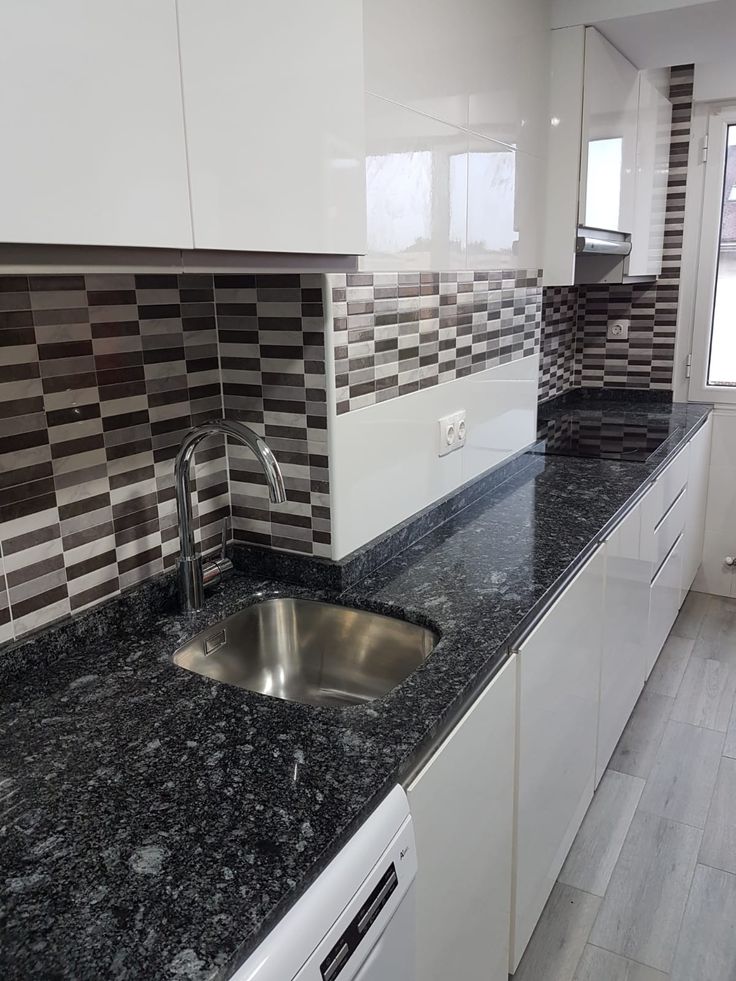 This may contain: a kitchen with black granite counter tops and white cabinets, along with a stainless steel sink