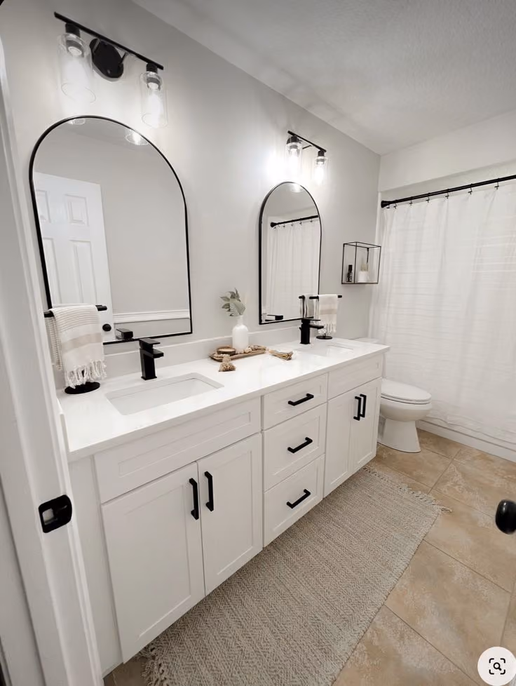 This may contain: a white bathroom with two sinks and mirrors