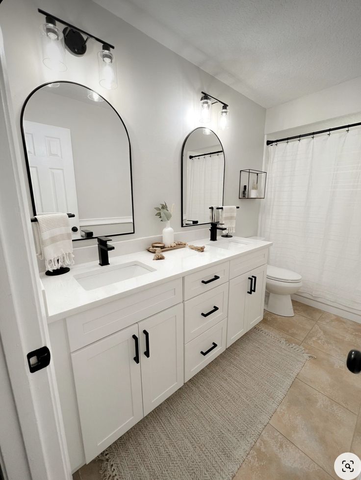 This may contain: a white bathroom with two sinks and mirrors