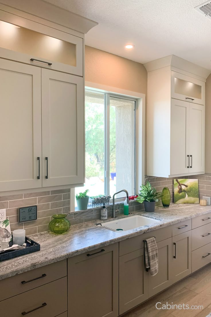 This may contain: a kitchen with white cabinets and granite counter tops, along with an open window to the outside