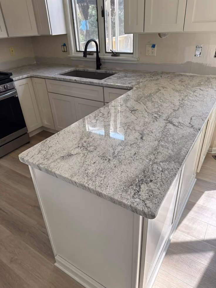 This may contain: a kitchen with white cabinets and granite counter tops in it's center island area
