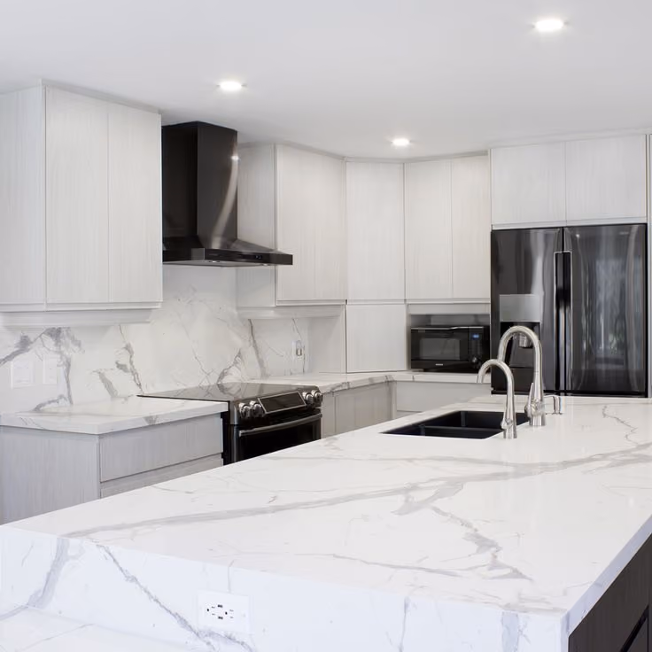 This may contain: a kitchen with white marble counter tops and black refrigerator freezer next to an oven