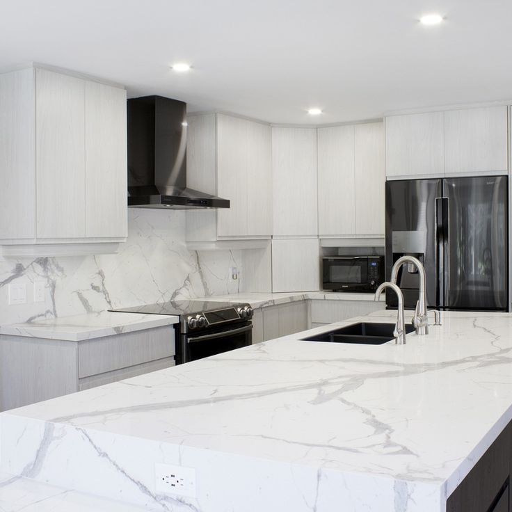 This may contain: a kitchen with white marble counter tops and black refrigerator freezer next to an oven