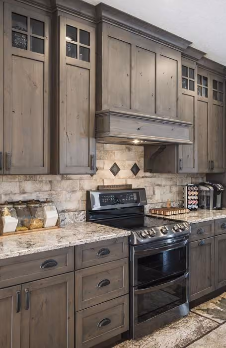 This may contain: a kitchen with wooden cabinets and granite counter tops, stainless steel appliances and an oven