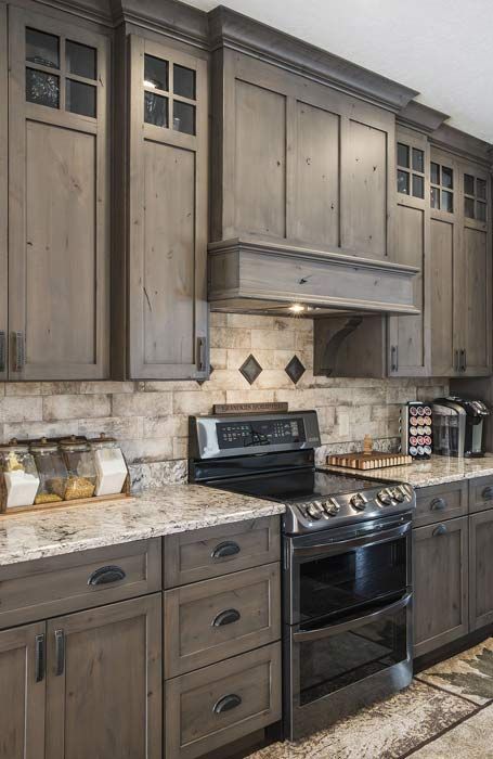 This may contain: a kitchen with wooden cabinets and granite counter tops, stainless steel appliances and an oven