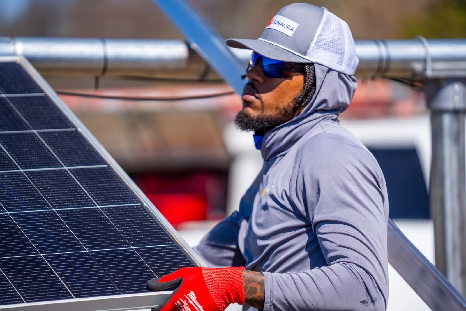 Licensed Sunaura Solar technician handling a solar panel during a home installation