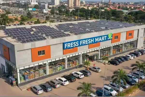 Aerial view of Fress Fresh Mart supermarket with solar panels on the roof and cars parked outside.