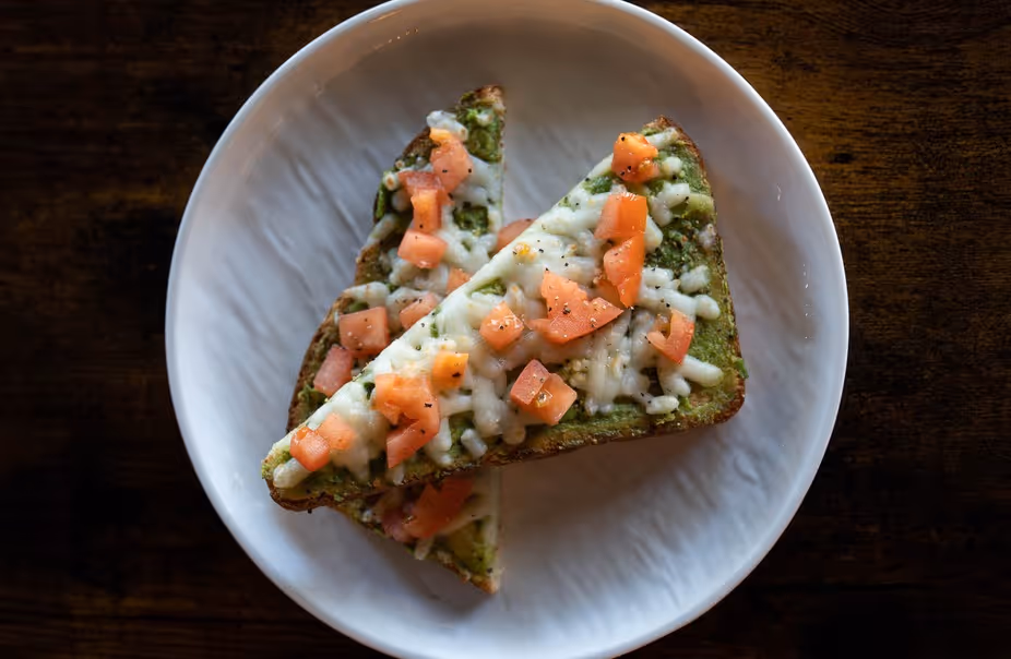 A slice of pizza with tomatoes and cheese on a white plate.