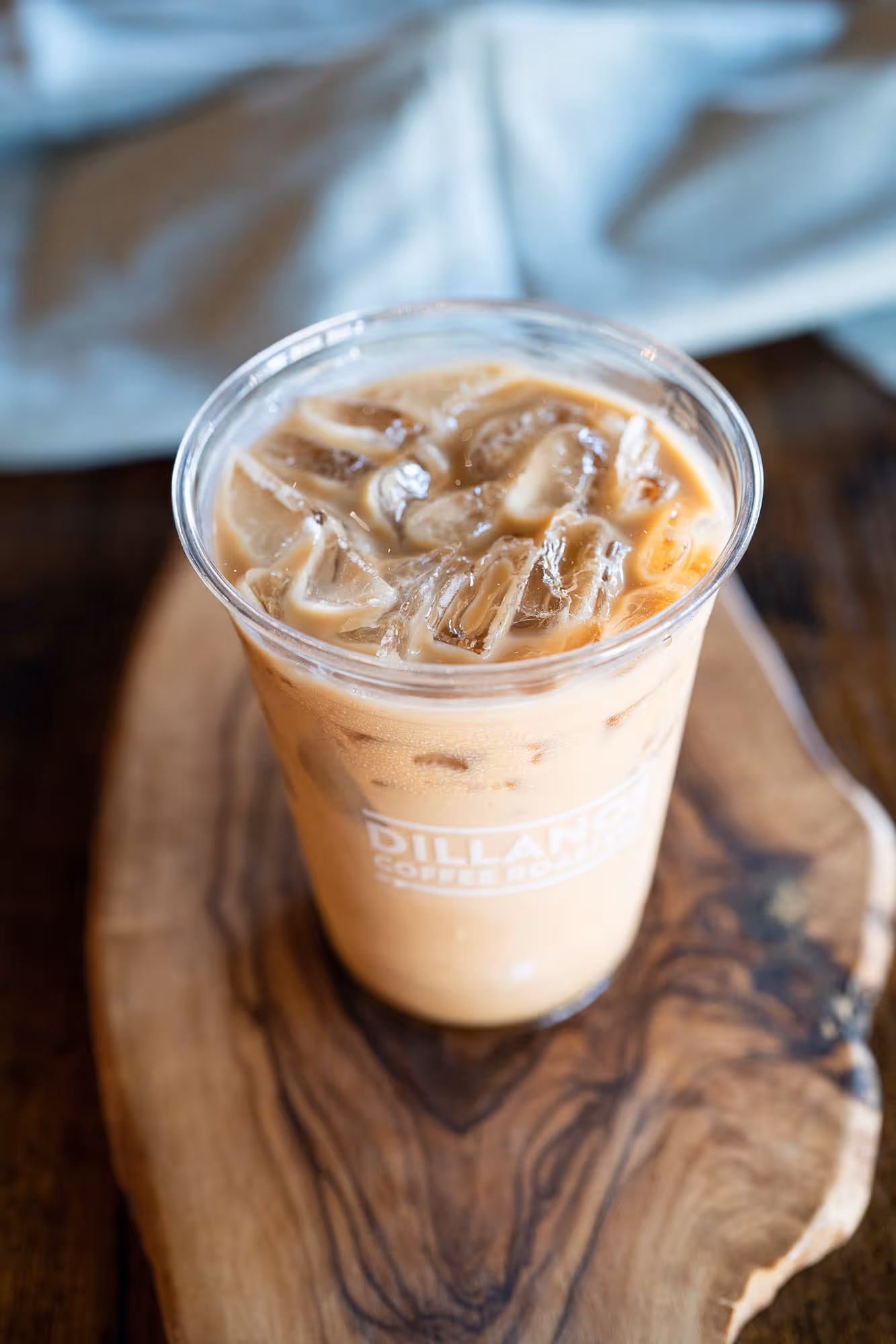 A cup of coffee with a wooden coaster underneath.