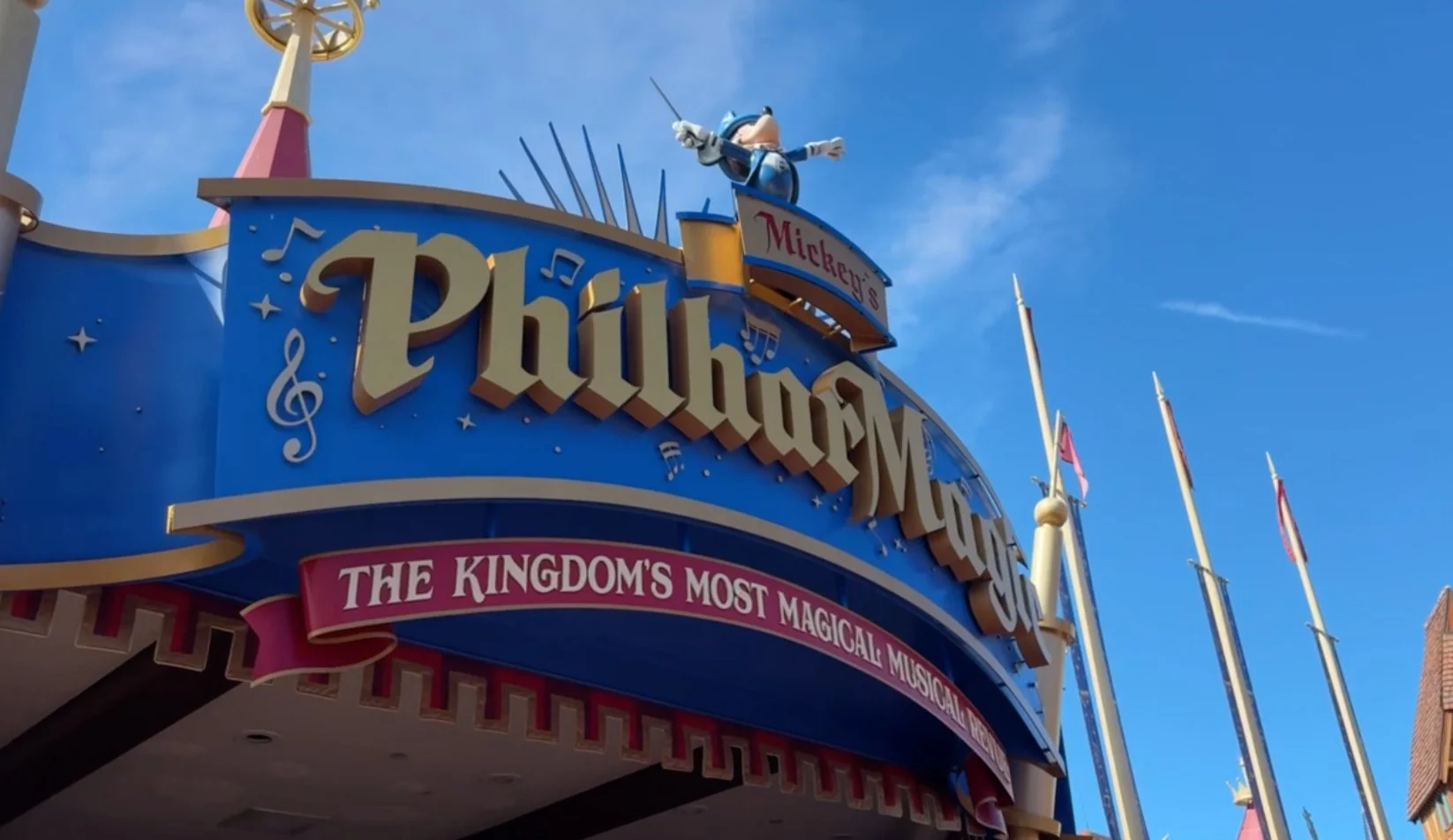 Mickey's PhilharMagic marquee at Magic Kingdom with Sorcerer Mickey and the tagline "The Kingdom's Most Magical Musical" against a blue sky.