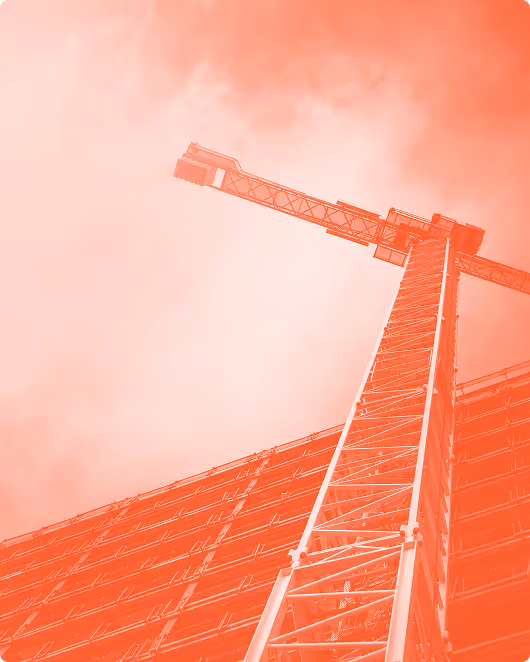 Upward view of a construction crane beside a building, tinted in red.”