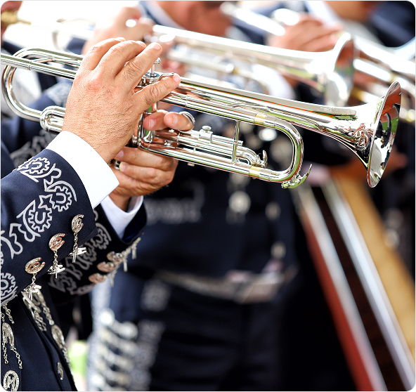 Mariachi musicians in traditional costumes playing trumpets and a violin.