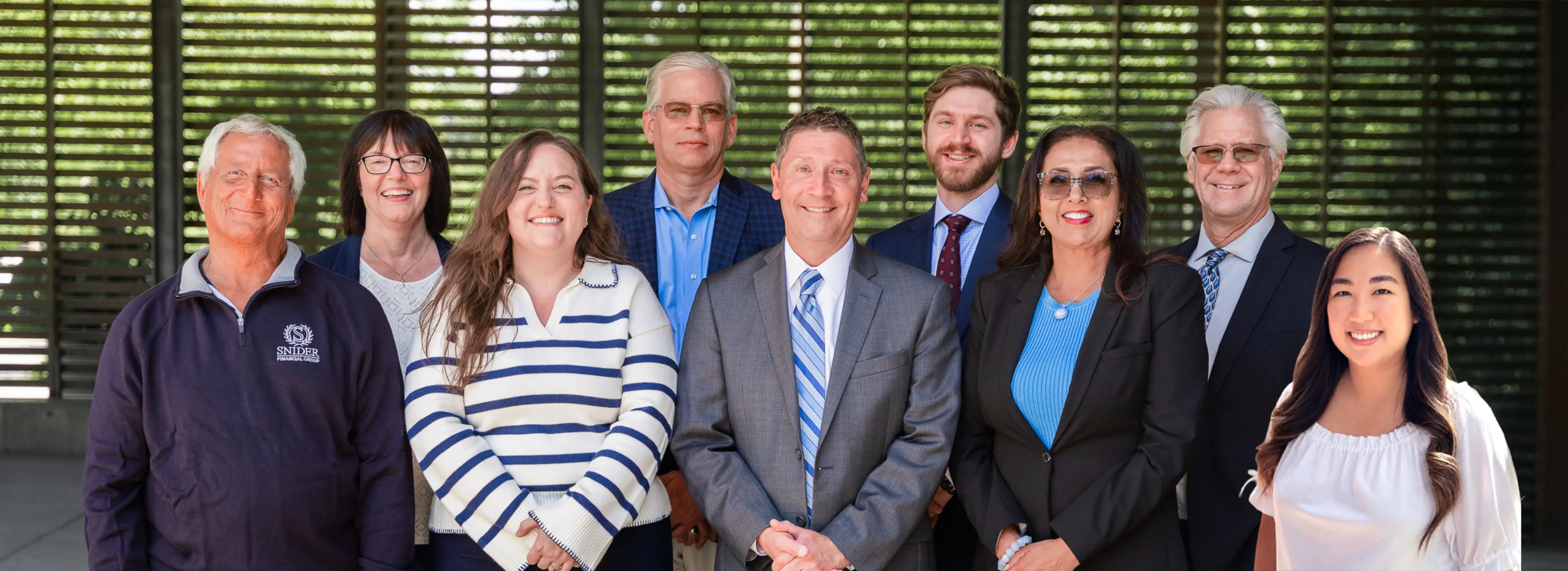 Group of Snider Financial Group employees posing and smiling outside.