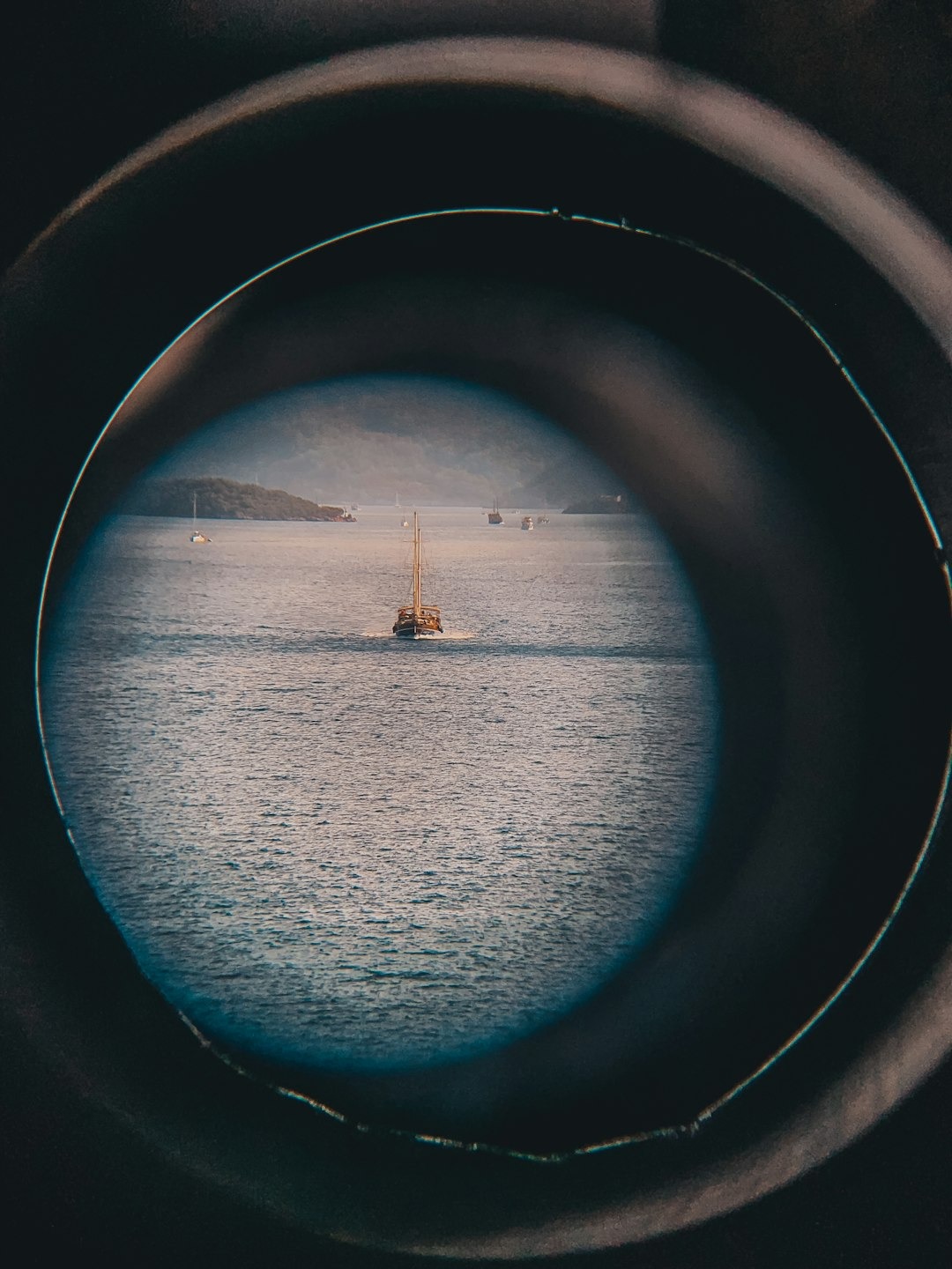 a view of a boat in the water through a porthole