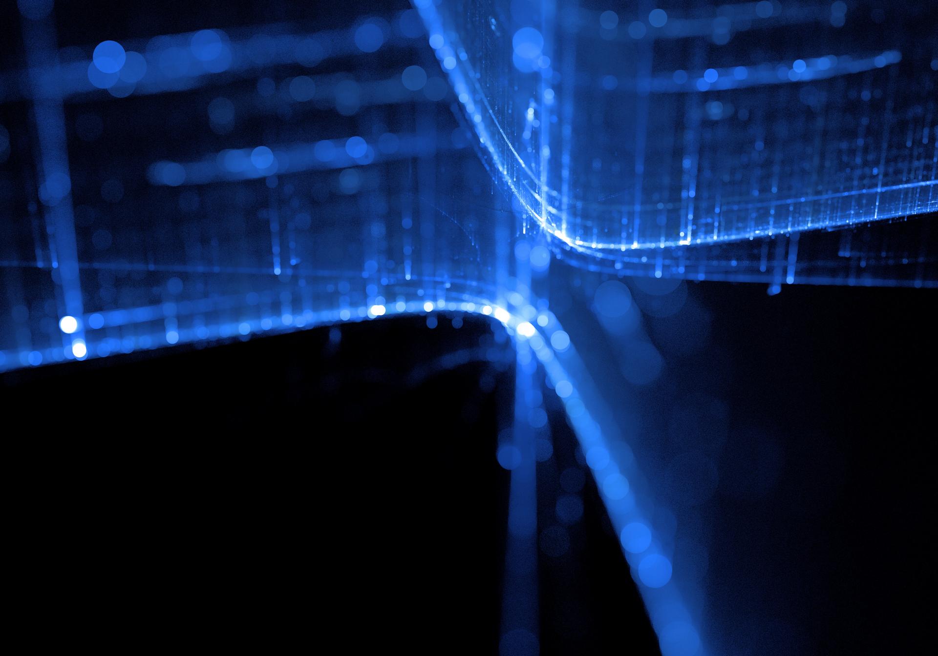 Abstract image featuring glowing blue lines forming a grid-like pattern against a dark background, creating a futuristic and digital aesthetic.