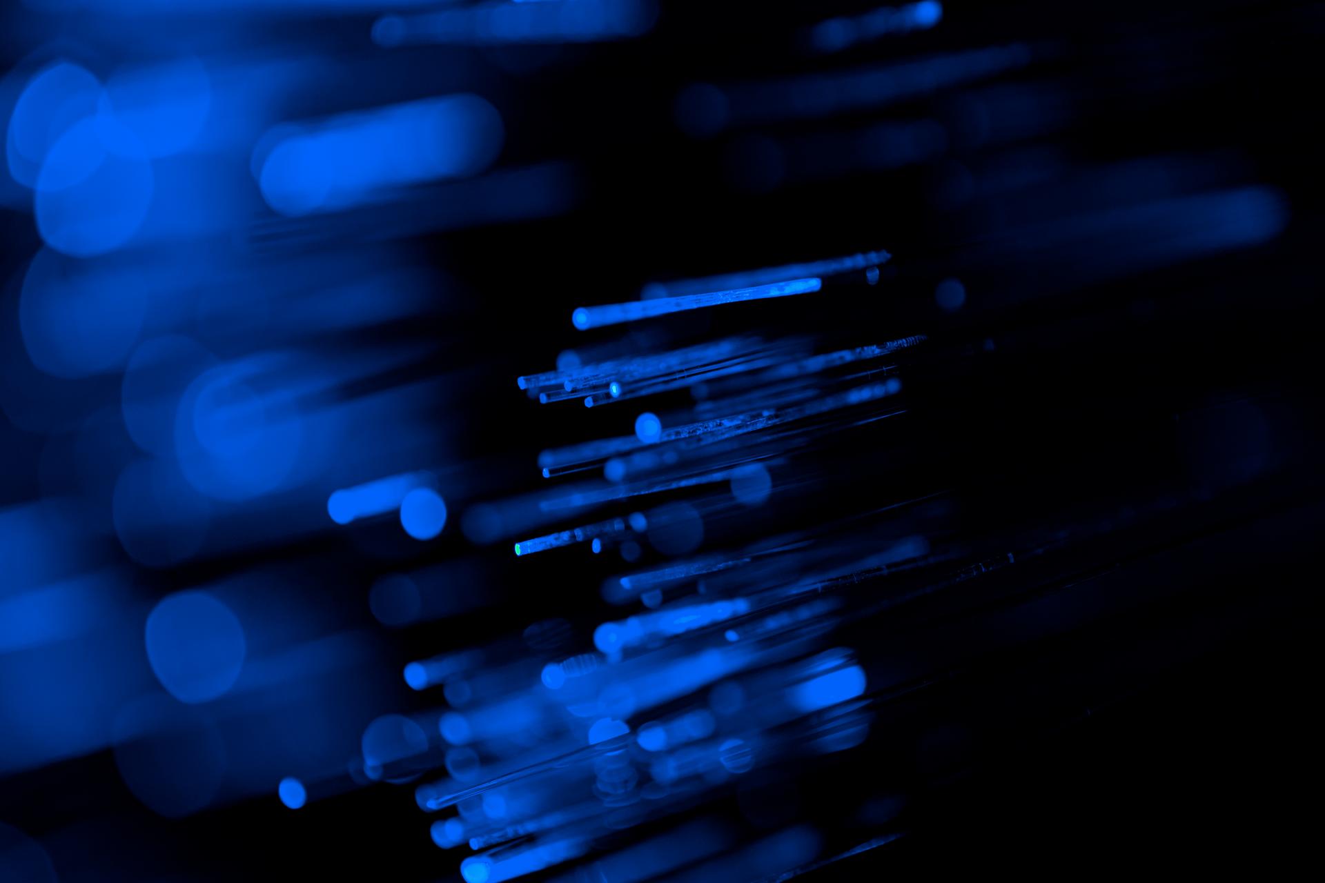 Abstract image of blurred blue lines and dots on a dark background, creating a dynamic, futuristic feel with a sense of movement and depth.