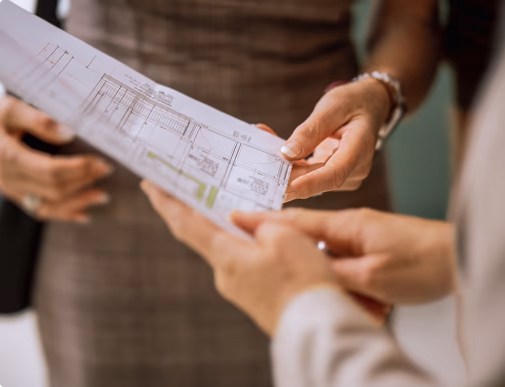 Zwei Personen, die Architekturpläne oder Grundrisse in den Händen halten und begutachten.