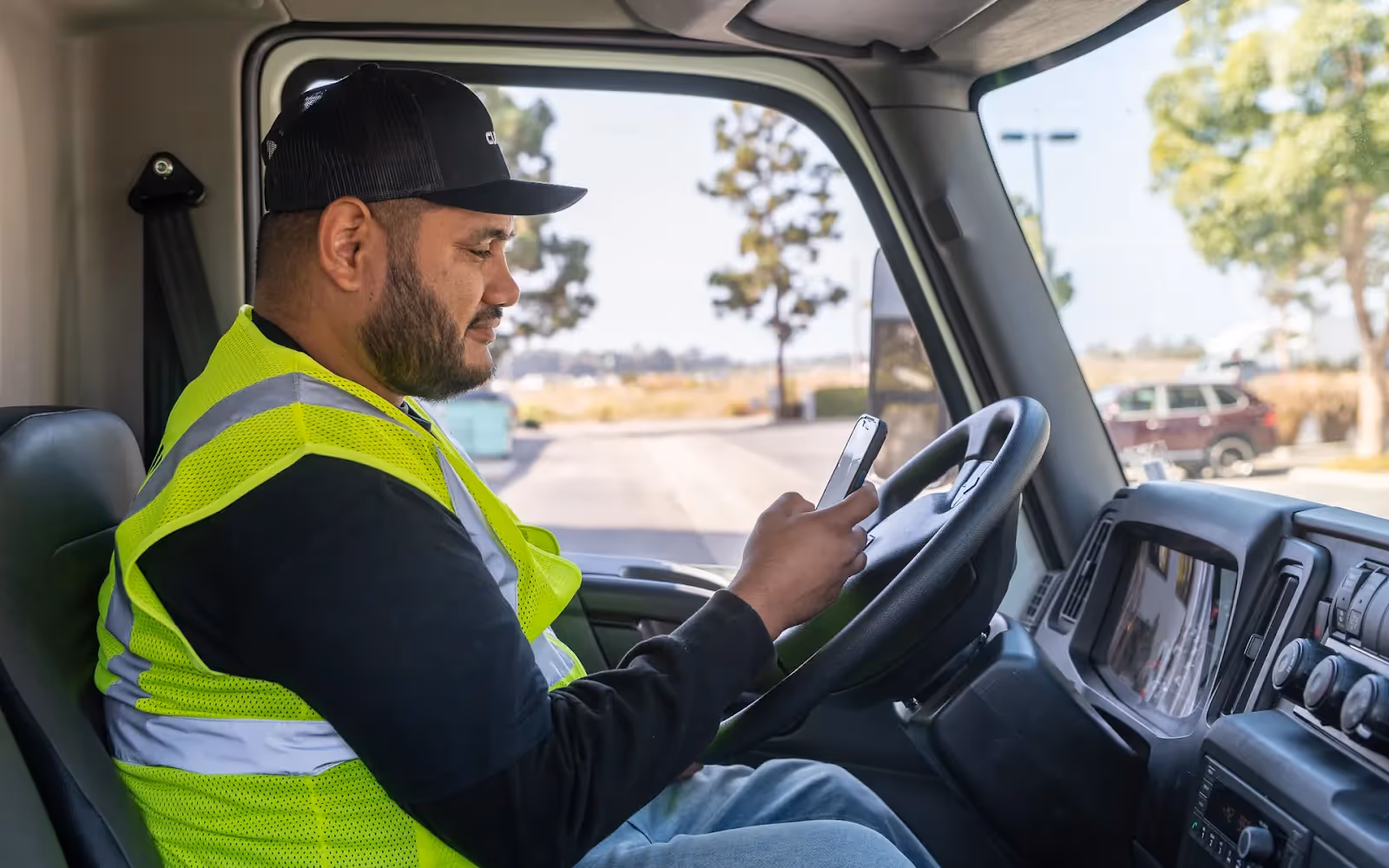 Image of a delivery driver sitting inside their vehicle and confirming delivery details on phone
