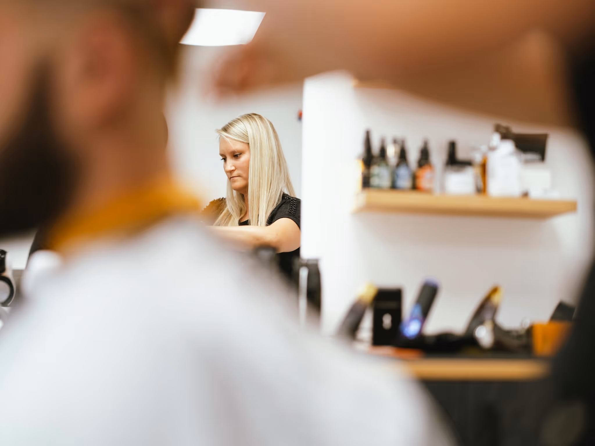 Slika Tine, lastnice brivnice, v daljavi, ki si striže lase