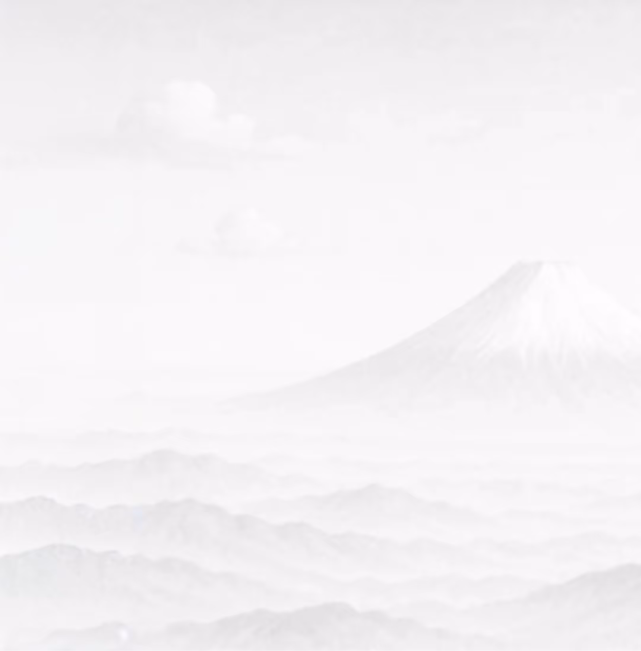 Faint image of a snow-capped mountain rising above layered misty hills with soft clouds.