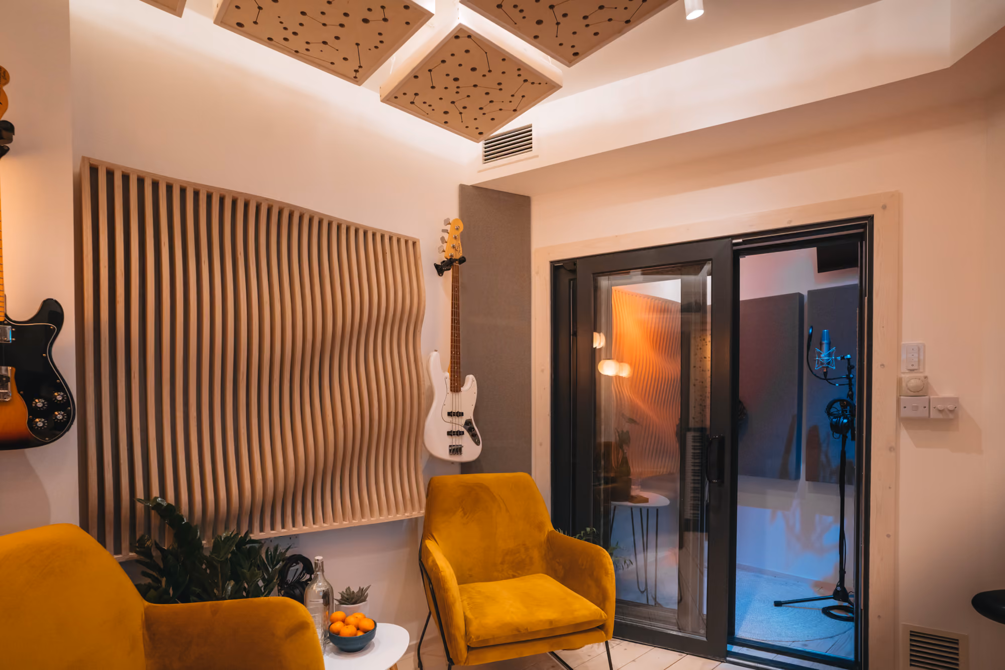 Studio B at Noatune Studios in Hackney: lounge with wooden acoustic diffuser, guitars and glass-door vocal booth