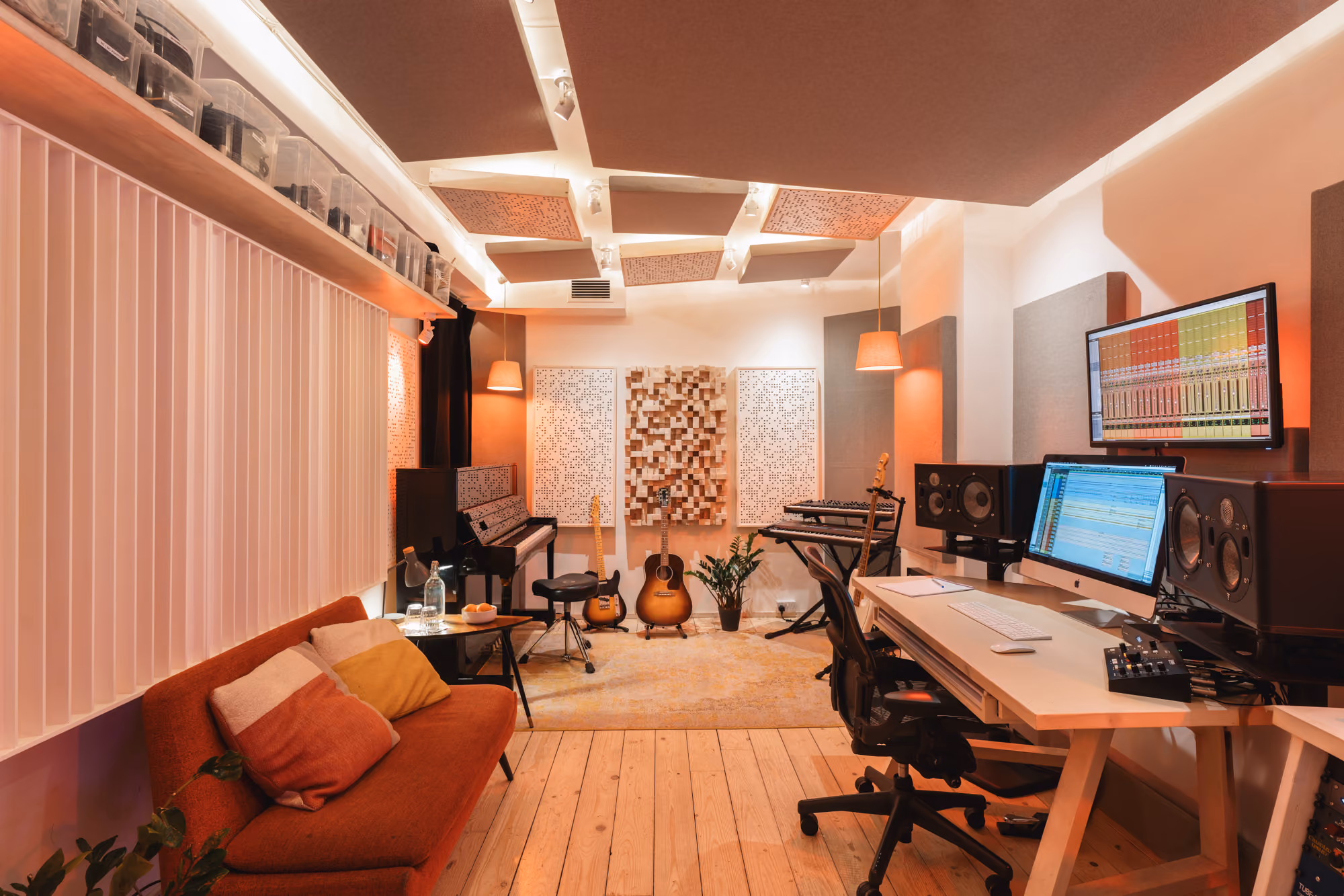 Recording studio at Noatune in Hackney with upright piano, guitars, sofa and tuned acoustic panels
