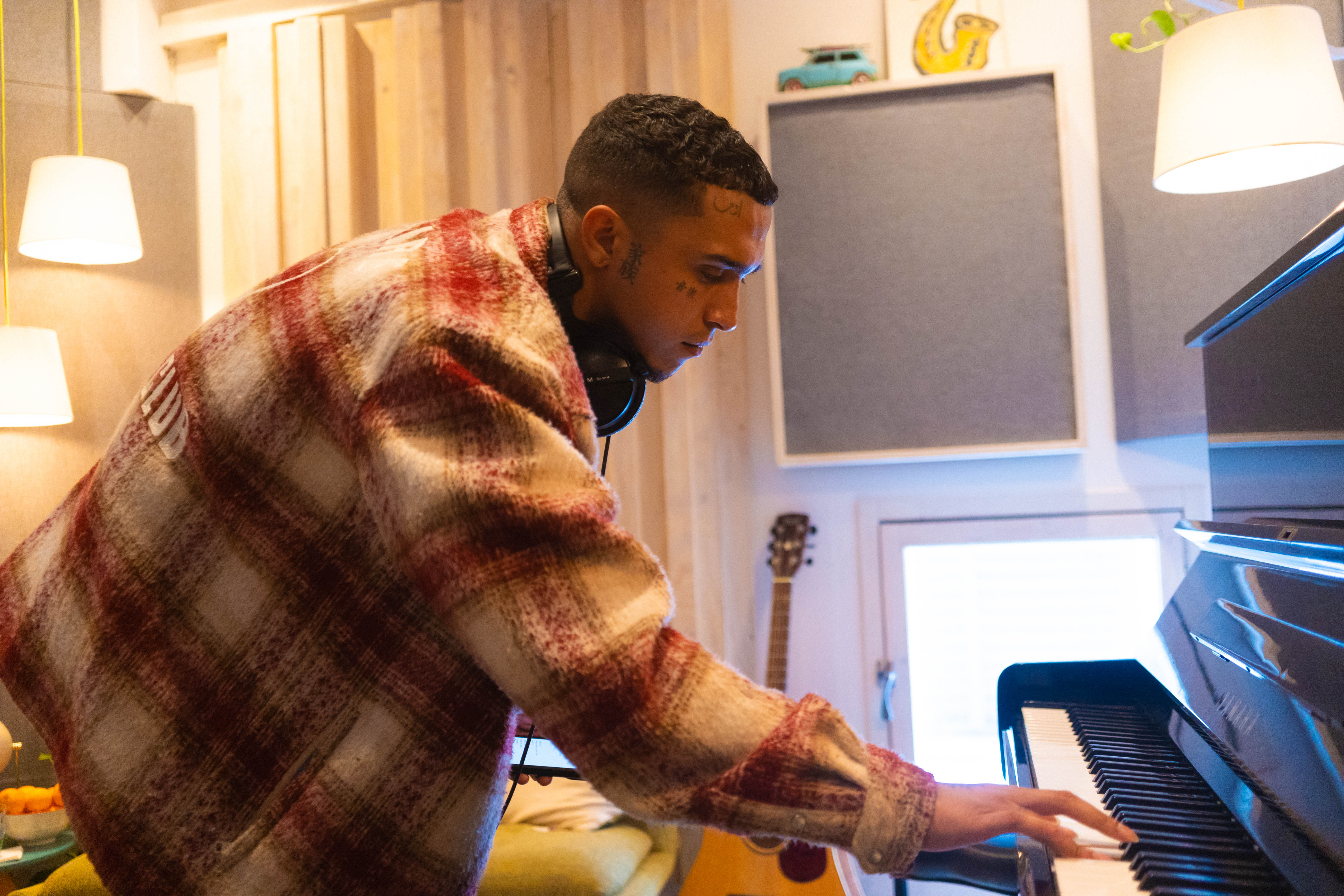 Male artist writing music and playing a Yamaha U1 piano in Studio D at Noatune Studios Hackney — a cosy, acoustically treated recording space available for studio hire in London.