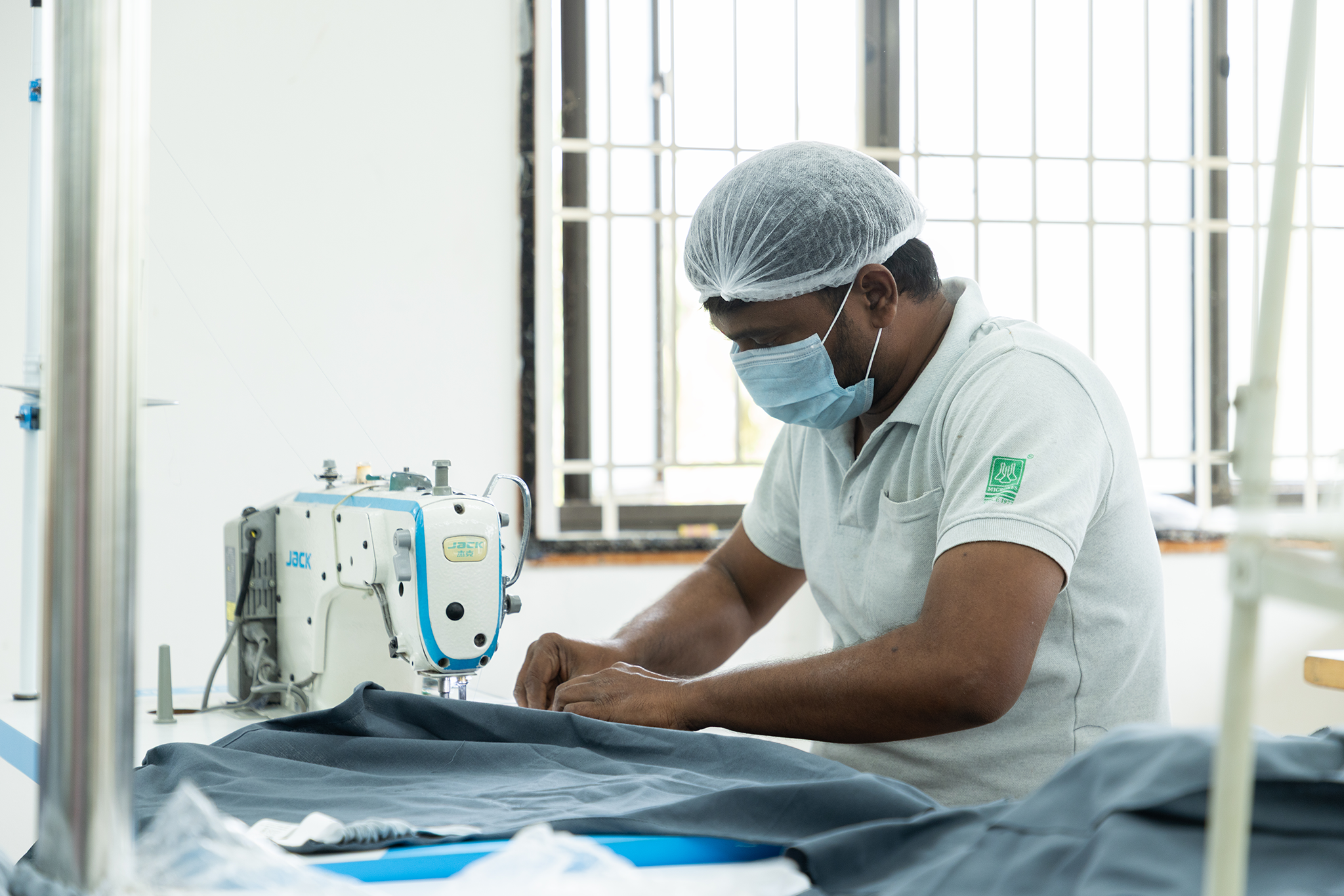 Man operating a sewing machine to stitch fabrics in Anubav Fabrics, Karur.
