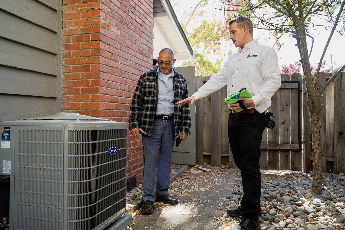IRBIS HVAC technician explaining air conditioning unit to homeowner.