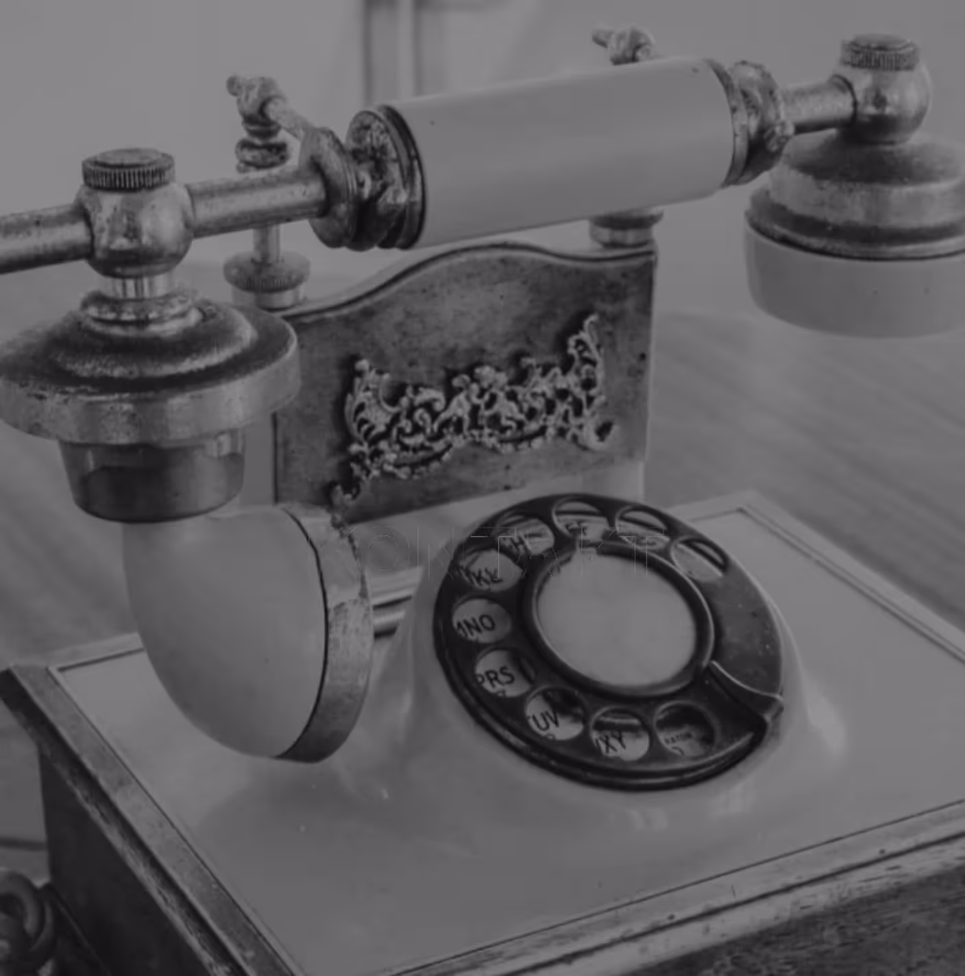 Nahaufnahme eines antiken Wählscheibentelefons mit verzierter Rückenplatte und metallischen Hörern.