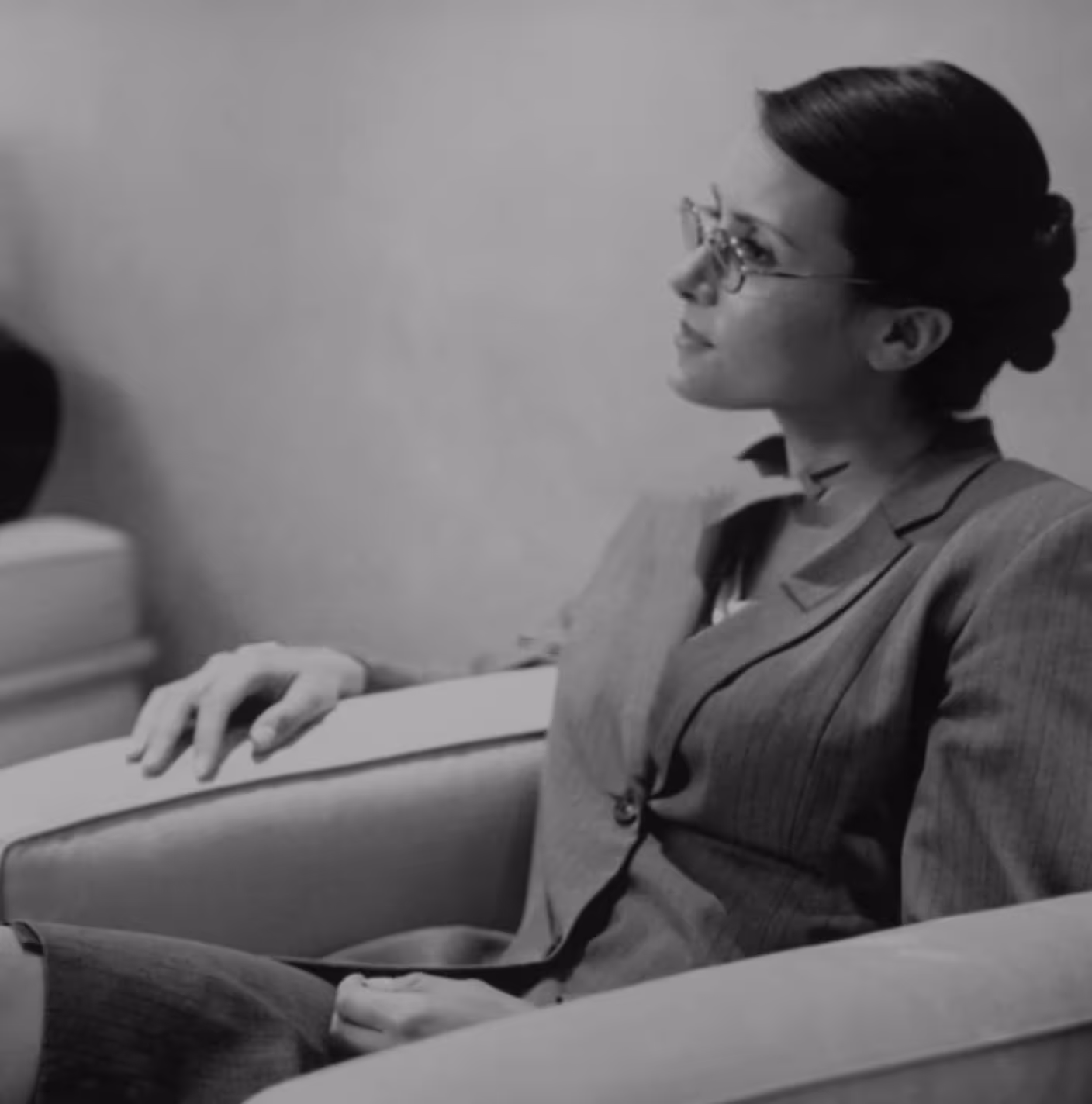 Professional woman in business attire with glasses, observing carefully