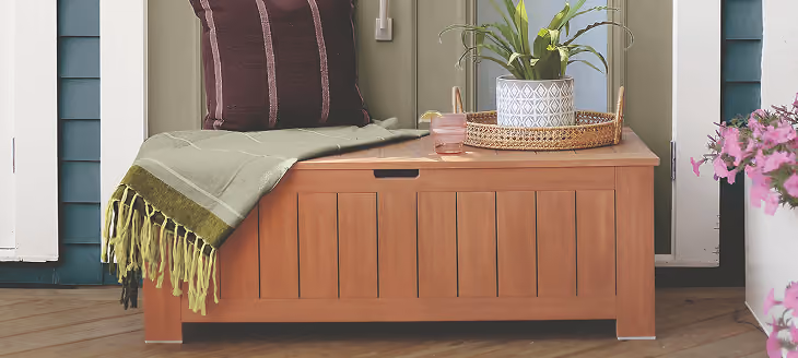 Wooden bench with pillows next to a blue wall with vertical wood paneling