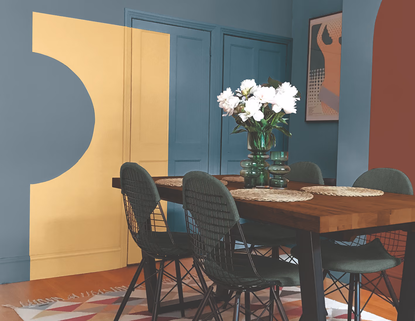 Modern dining area with blue walls, a wooden table, and geometric shapes in the background