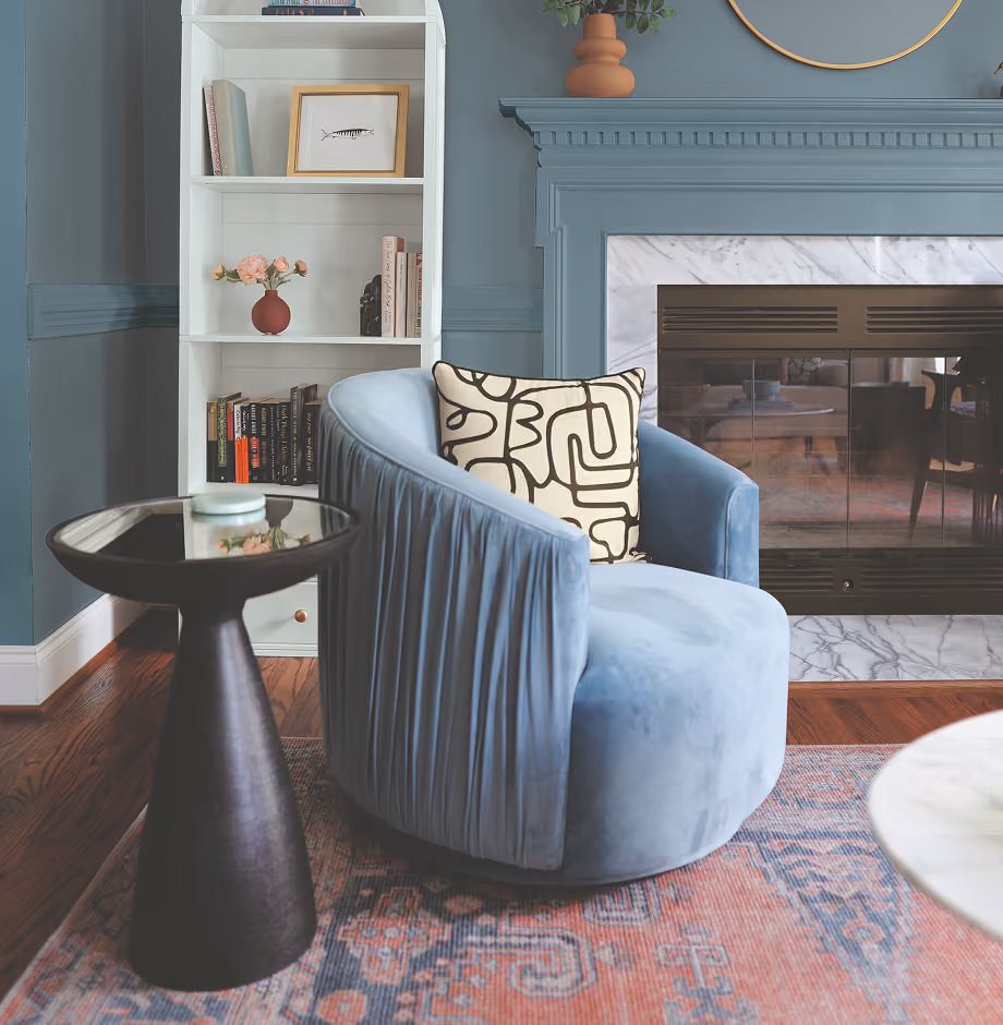 Cozy living room interior with a blue armchair, a blue fireplace mantle, and white shelving