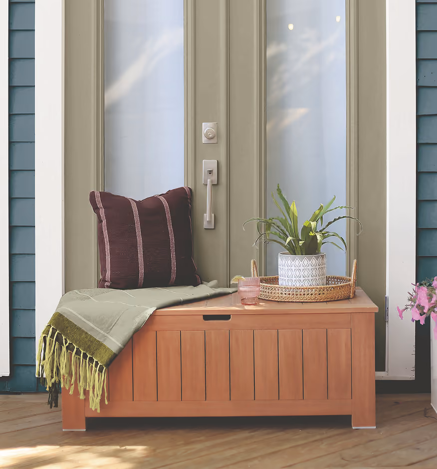 Wooden bench with pillows next to a blue wall with vertical wood paneling