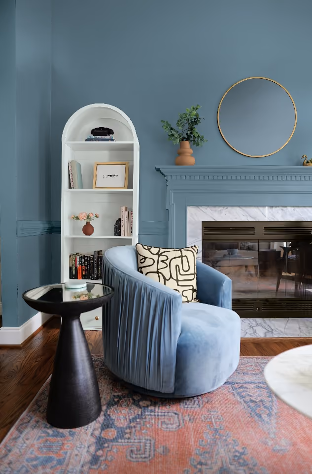 Blue living room featuring a fireplace, a round gold mirror, and a light blue armchair
