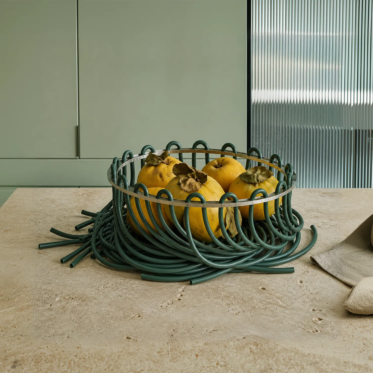Green Lace fruit bowl holding yellow fruit on a kitchen worktop.