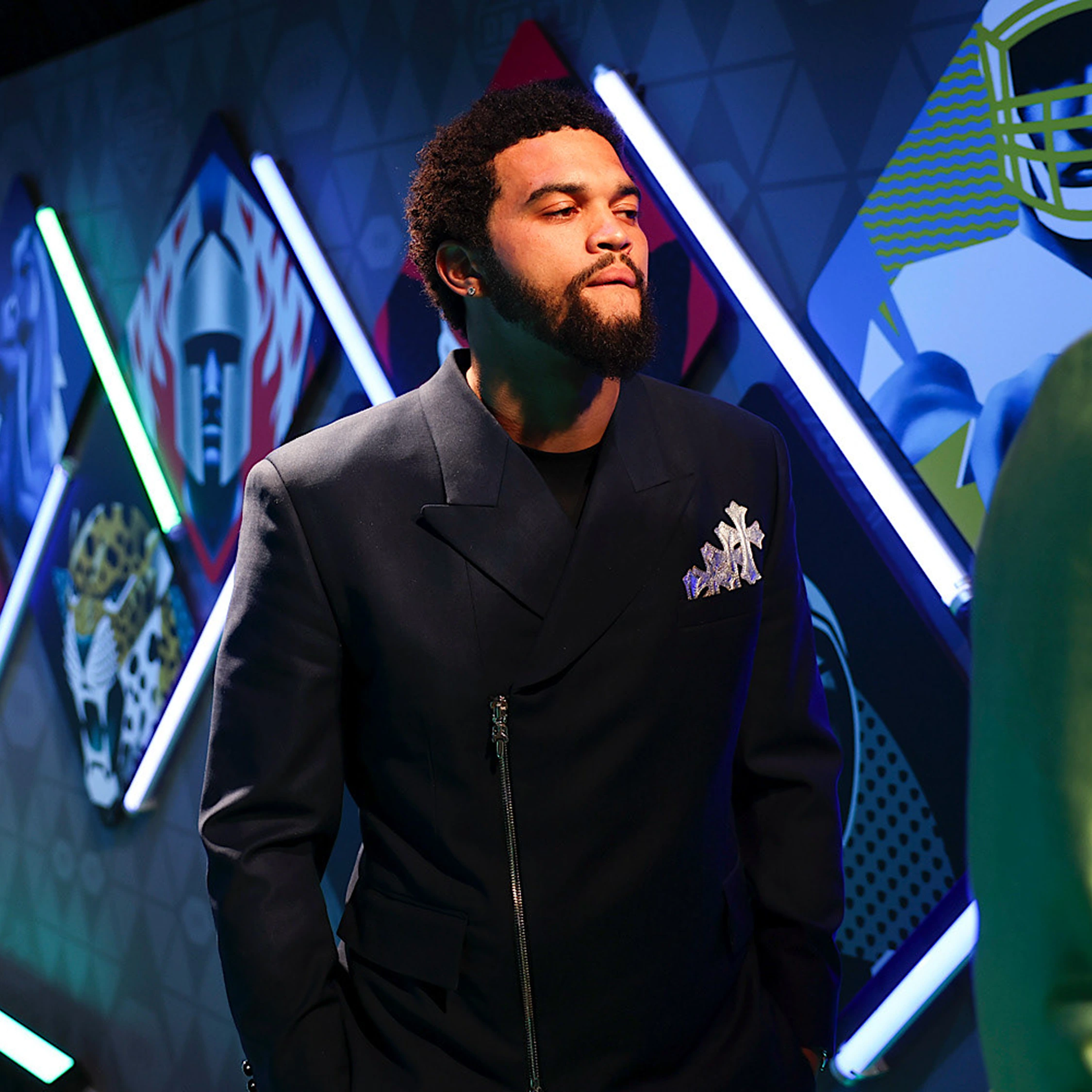 A person in a dark suit at an event with angular blue illuminated scenery.