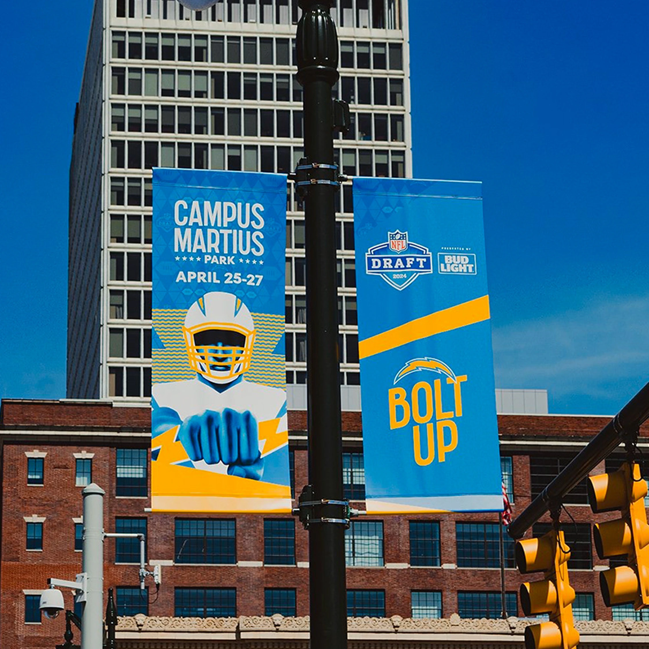 Blue and yellow event banners displayed on a city street beneath a clear sky.