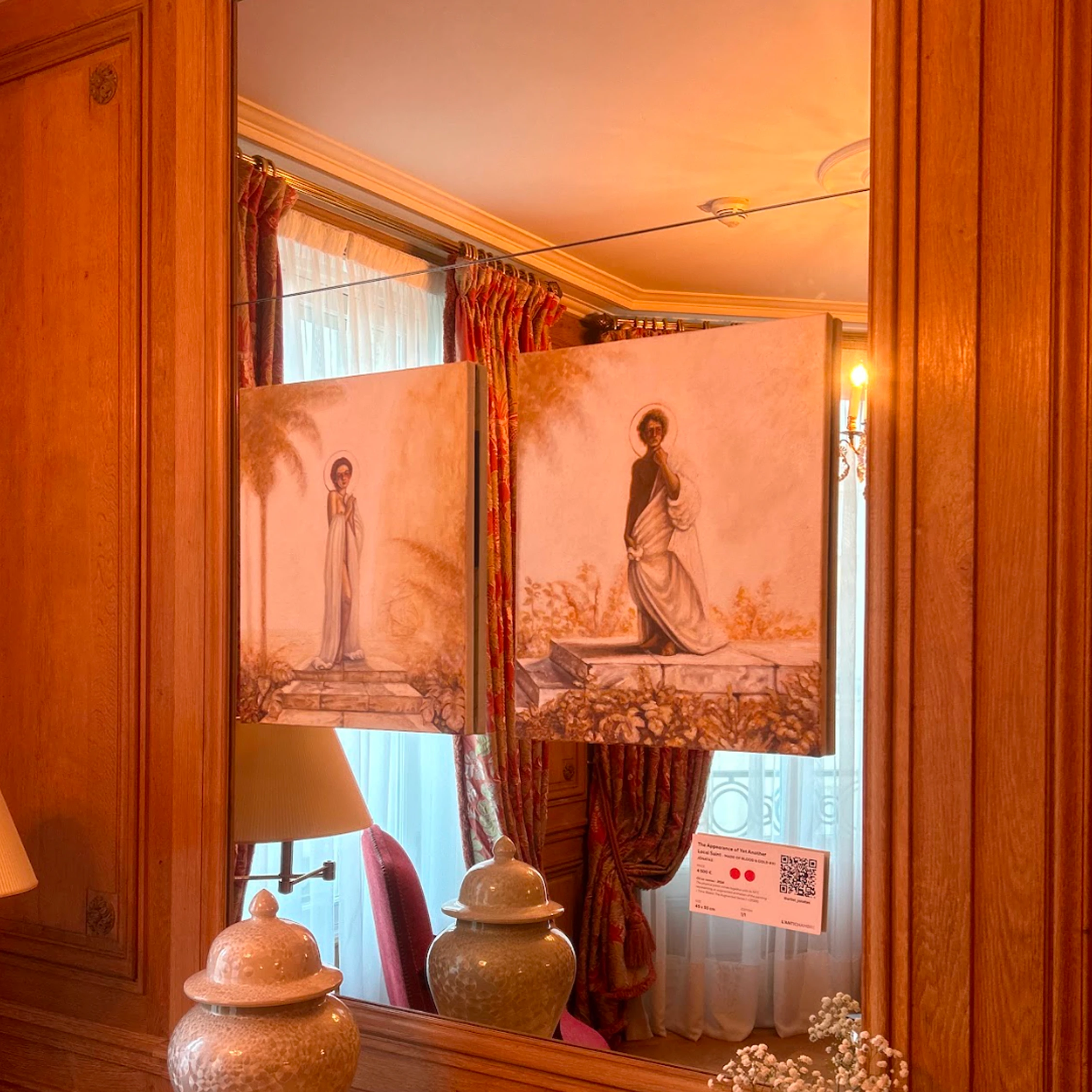 Two suspended painting panels in a warmly lit interior.