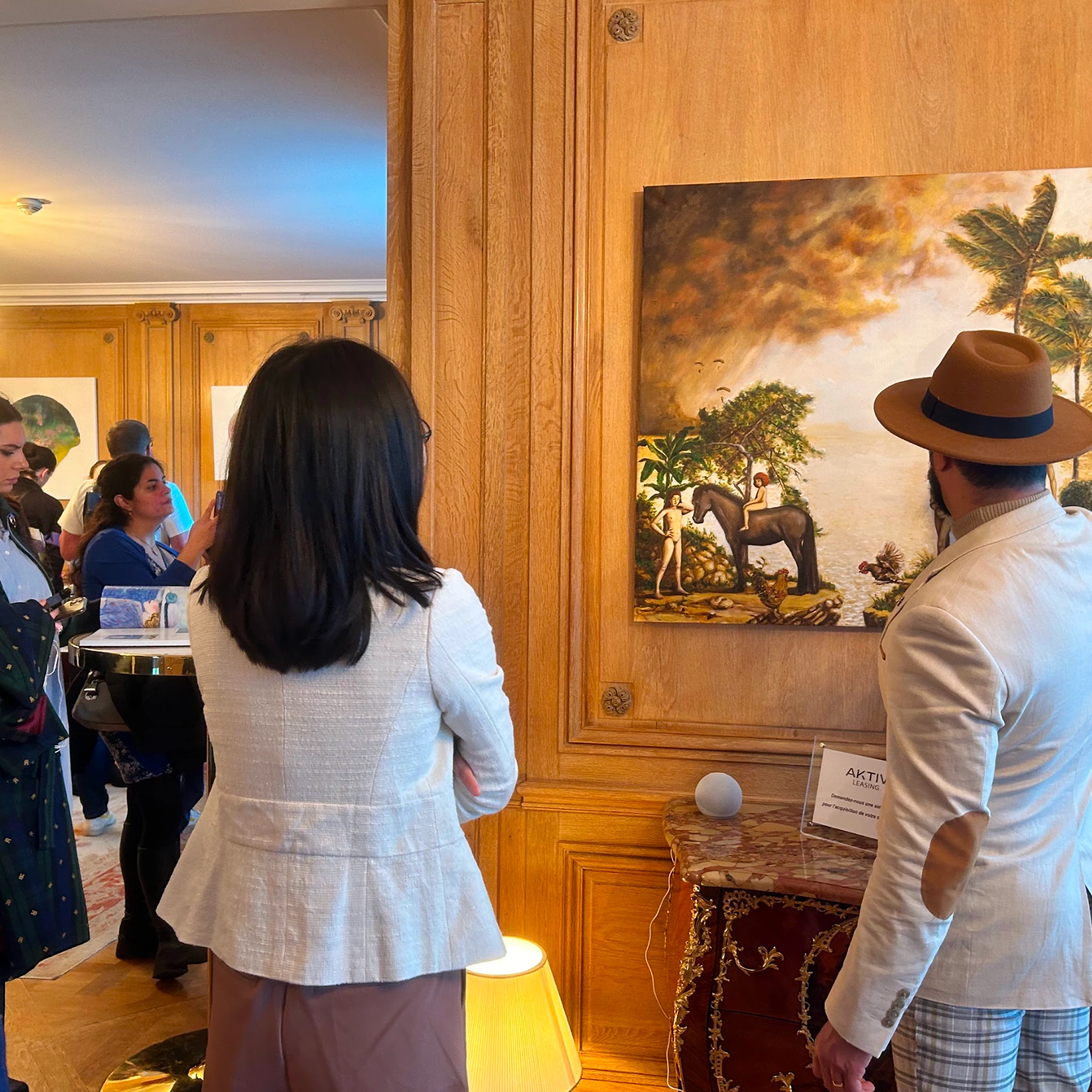 Two visitors facing a painting on a wood-panelled wall.