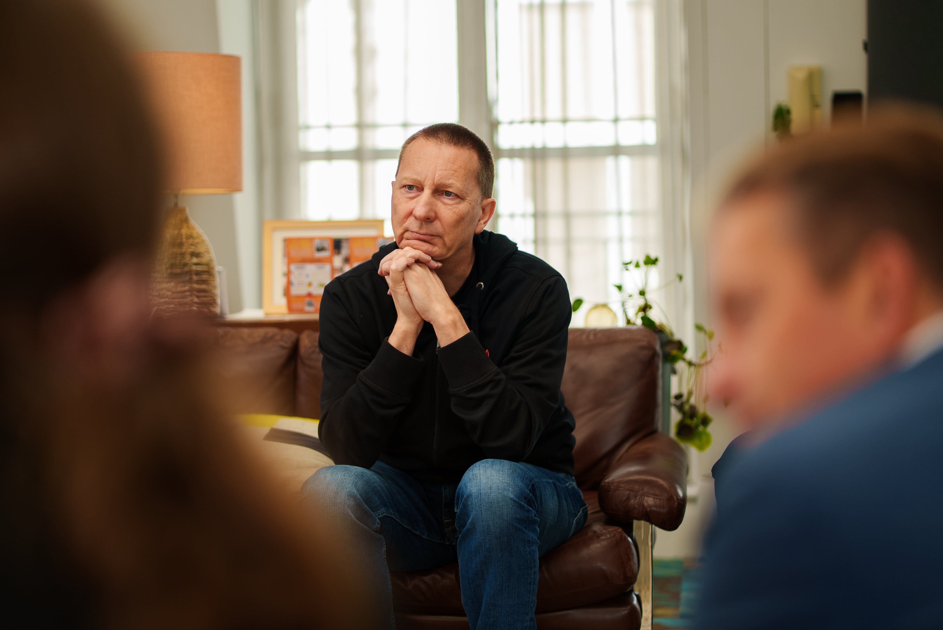 Damon Mannion sitting on a sofa, talking with team members.