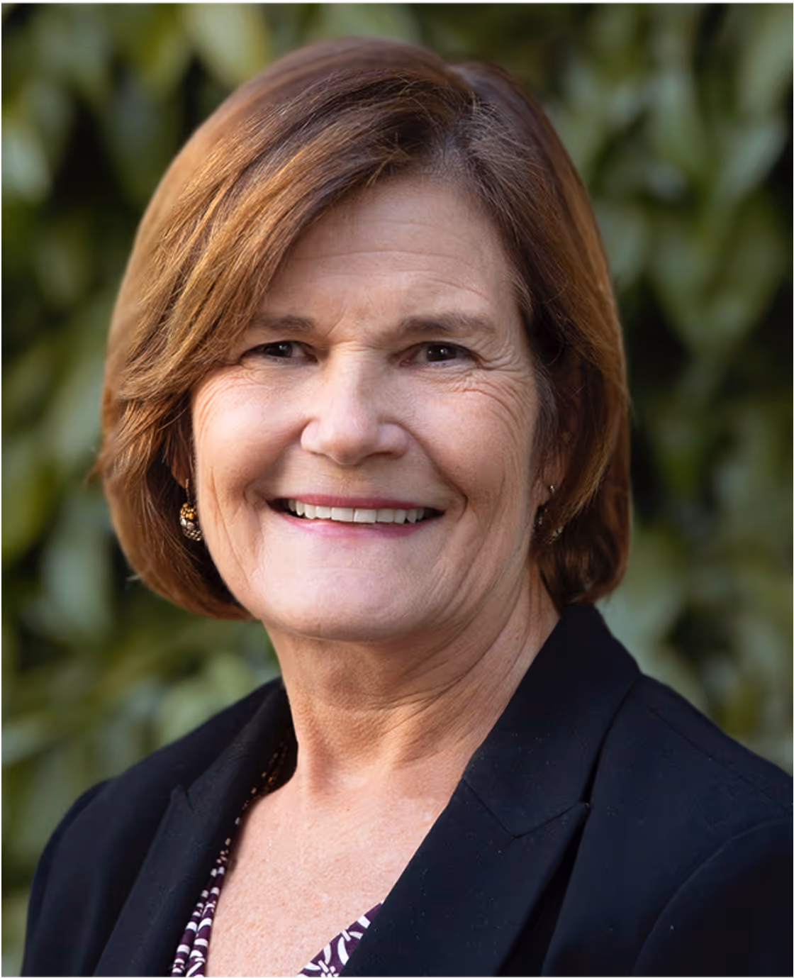 Headshot of Deirdre Mahlan, a woman with short blonde hair, smiling in a dark blazer.