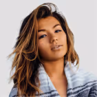 Young woman with long brown hair wearing a striped blue and white sweater against a light background.