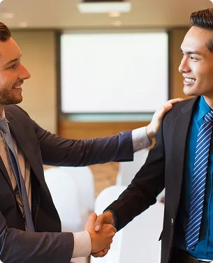 Two businessmen shaking hands and smiling during a meeting in an office.