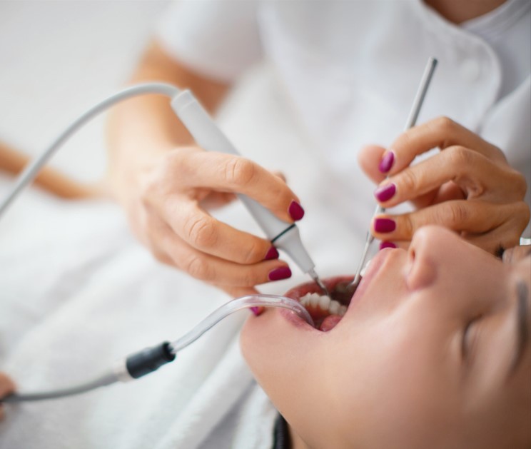 Dental professional using tools to clean a patient's teeth during a dental procedure.